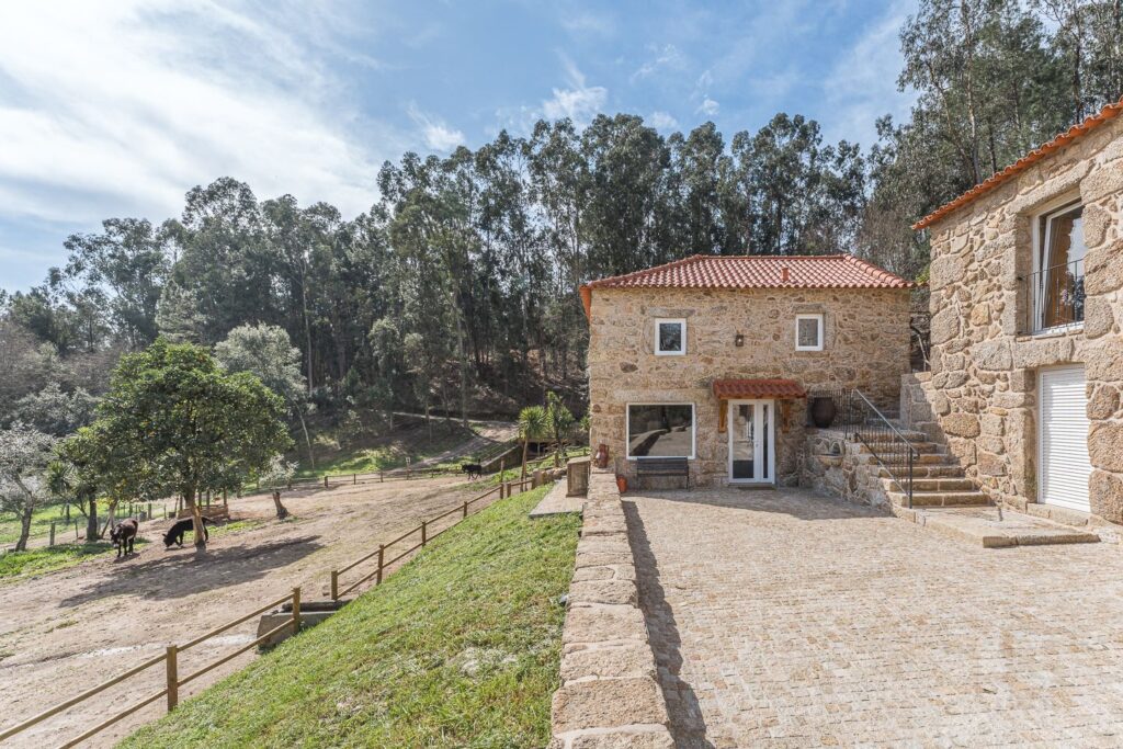 Casa do Burro em pedra, com os burros no cercado ao lado