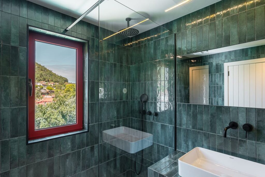 Casa de banho de azulejo verde com janela para o vale
