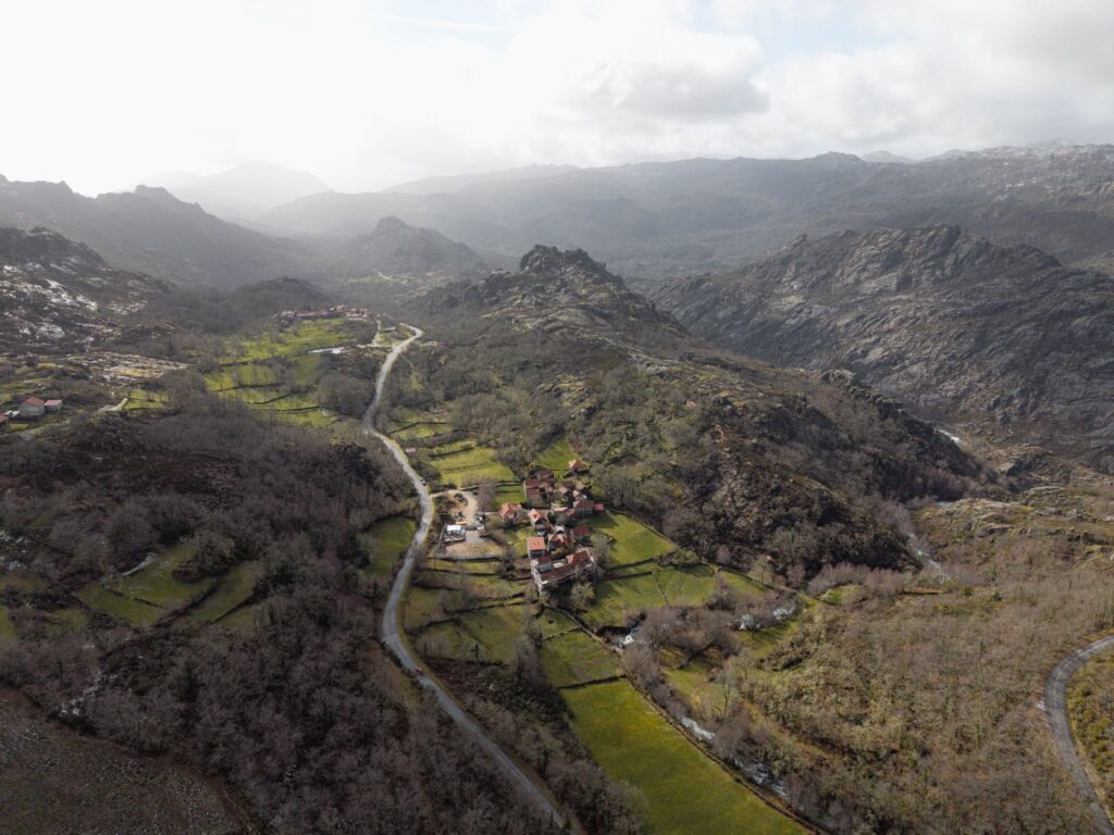 O vale com a aldeia pequena ao centro e as serras com neblina