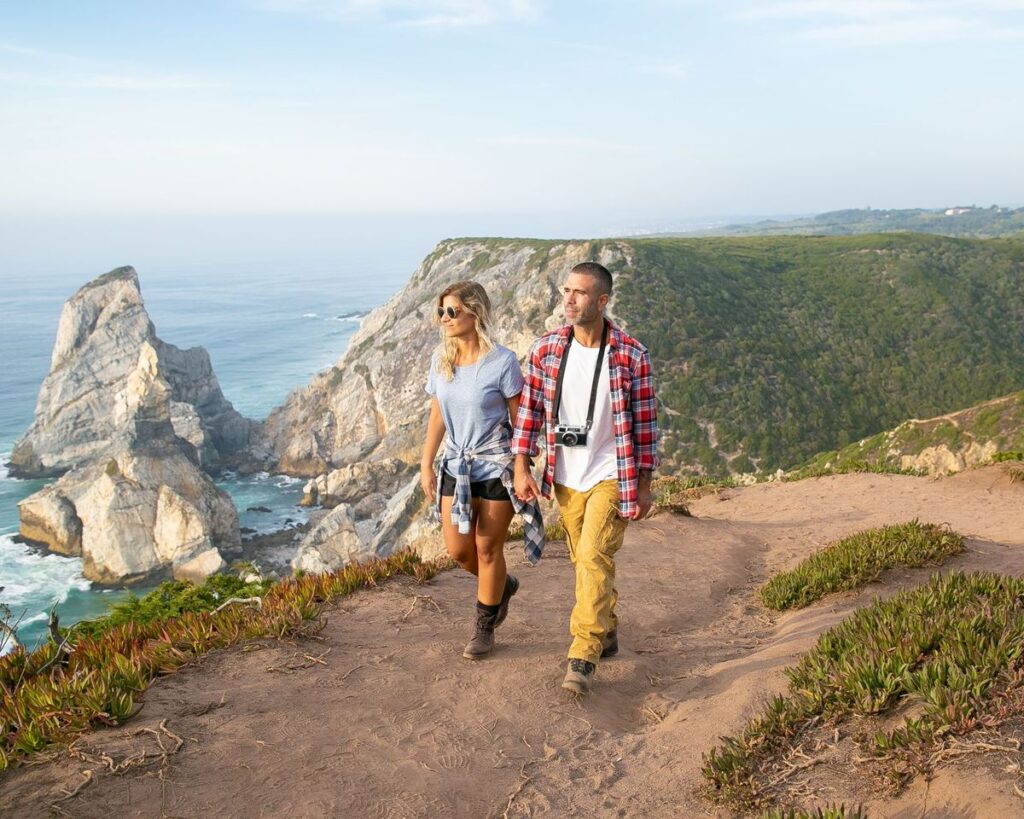 Duas pessoas numa caminhada num trilho junto ao mar
