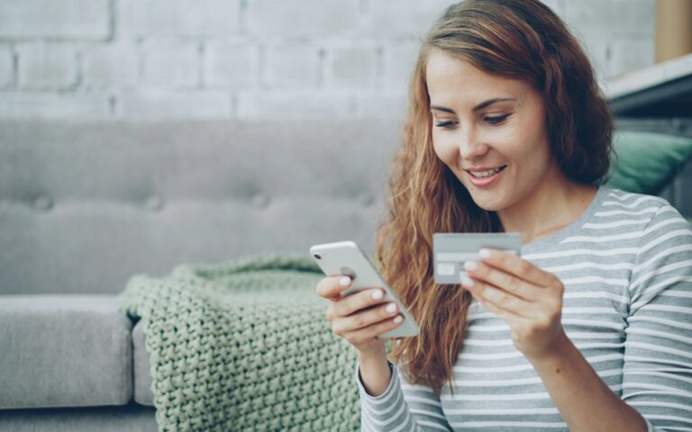 Hóspede a pagar a reserva online no telemóvel, com o cartão na mão