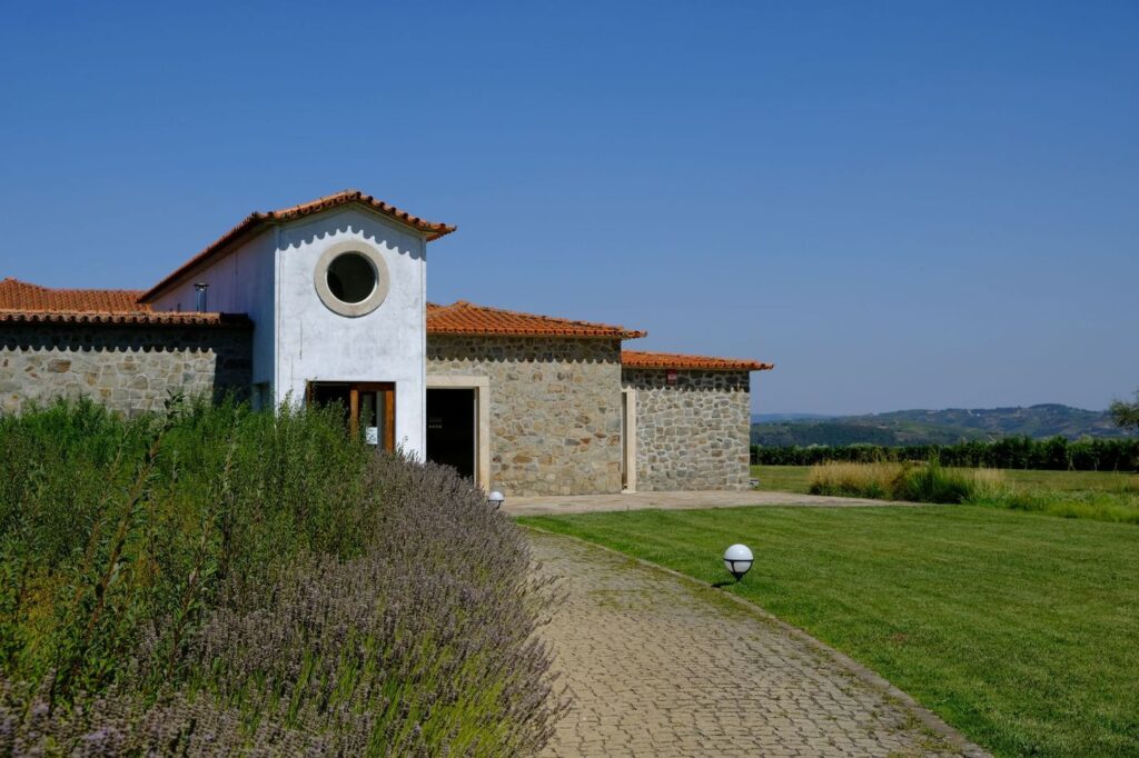 Casa de pedra com telhado de telha numa quinta, com relvado e alfazema