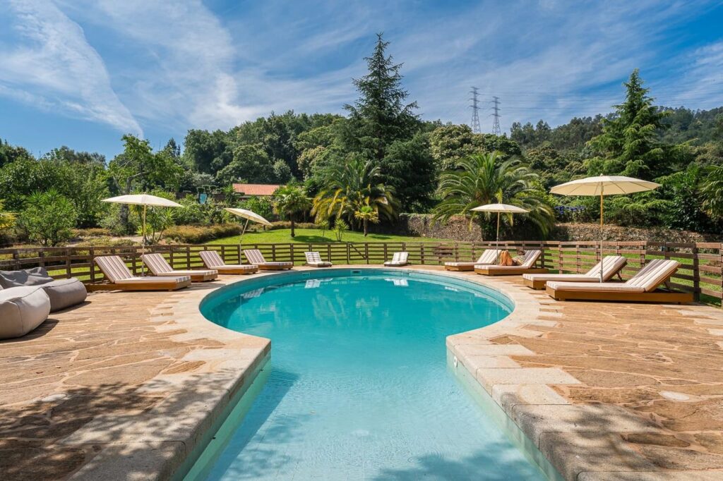 Piscina rodeada de espreguiçadeiras e guarda-sóis