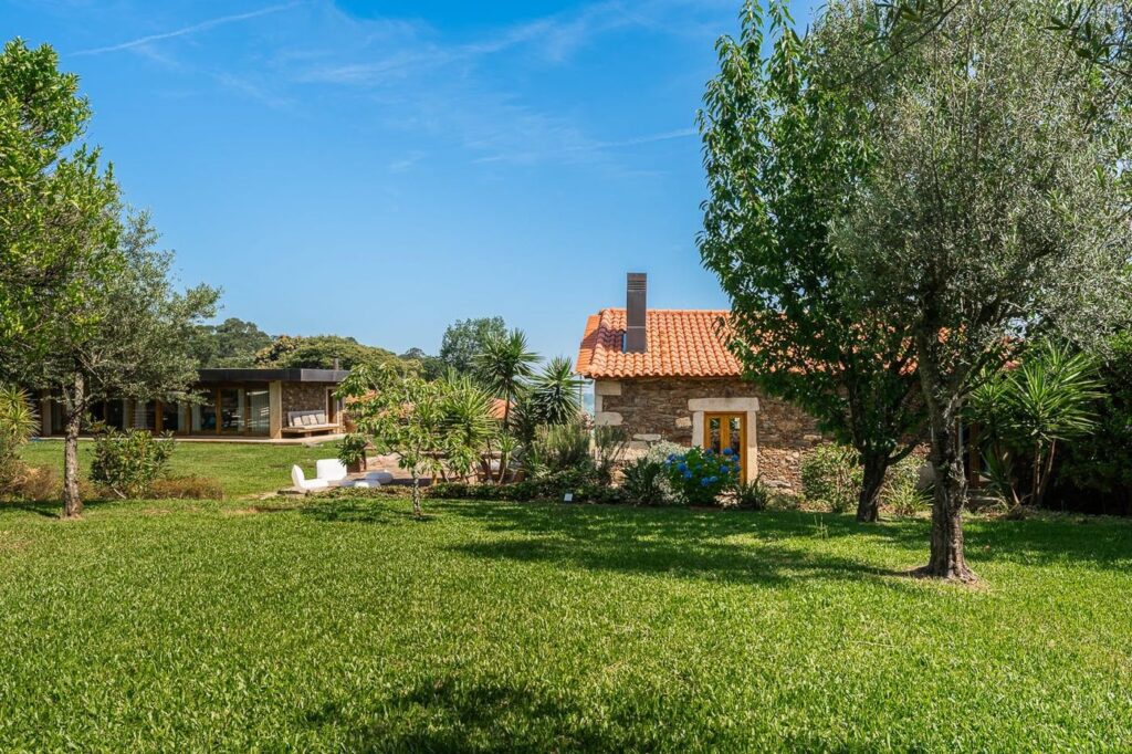 Jardim com árvores, a Casa da Piscina e a Casa da Eira ao fundo