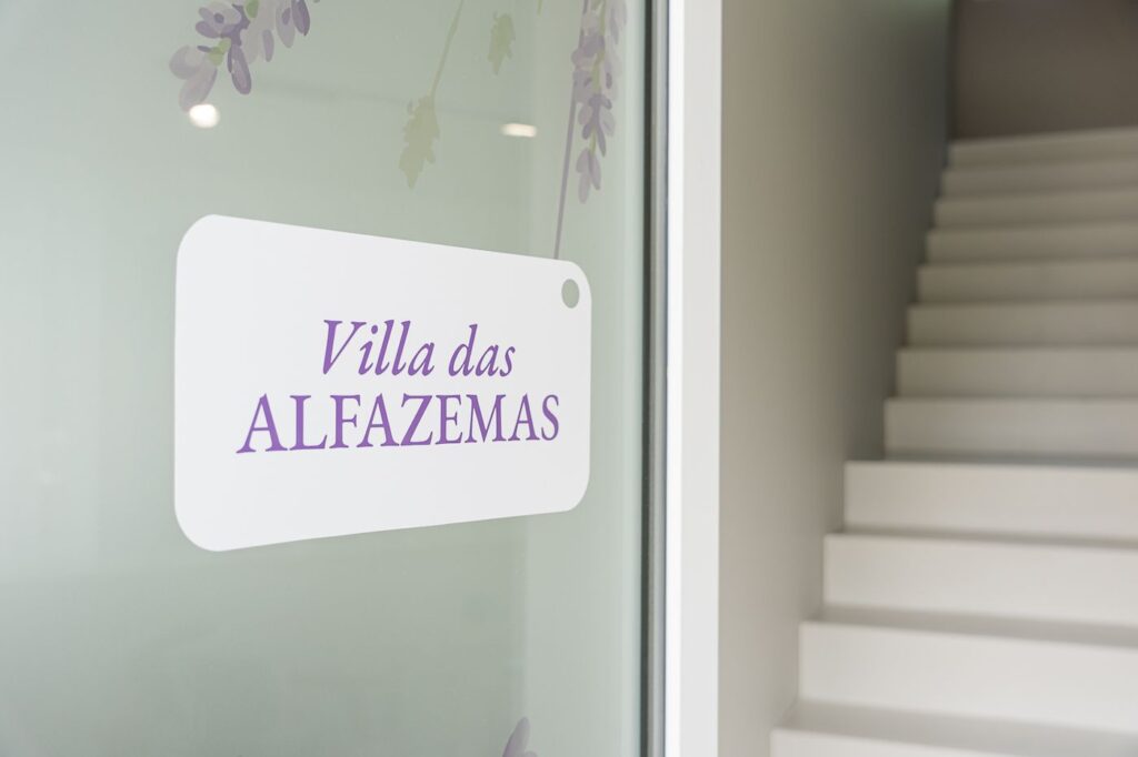 Placa da Villa das Alfazemas na porta de vidro